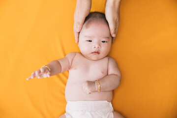 Asian Baby with his mothers hand on his head