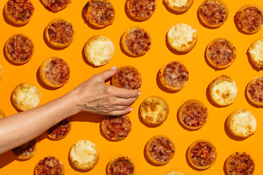 Woman holding mini pizza appetizers on colorful background