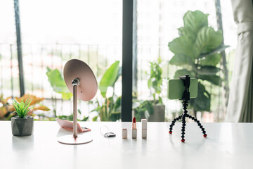 Set of cosmetics and mirror with mobile on tripod ready for livestream