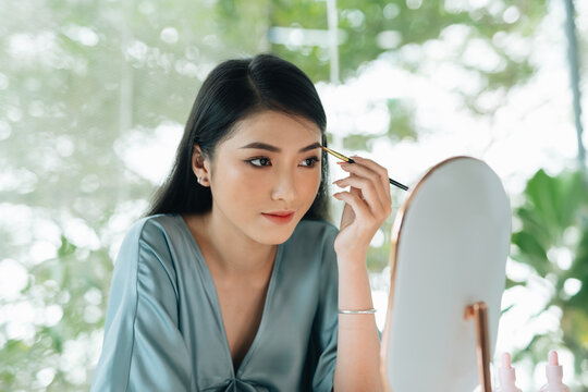 Girl draws eyebrows with a shade and define the shape of eyebrows