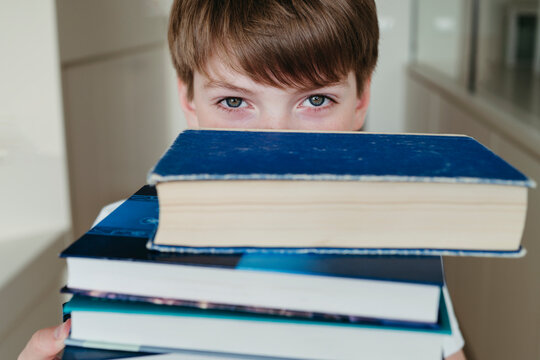 Closeup boy with stack of books.