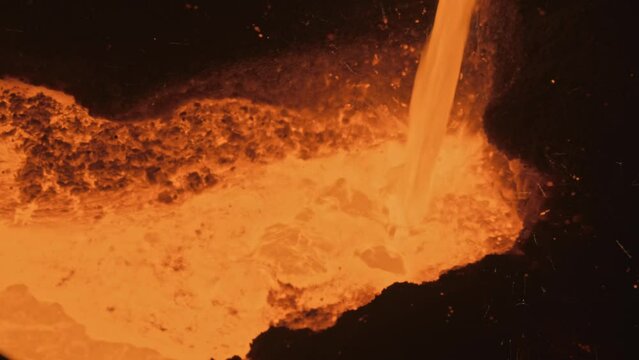Molten metal flows into a vat of liquid iron at a metallurgical plant