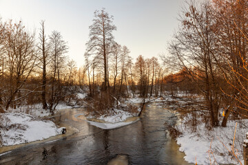 sunset on a river whose banks are covered with ice