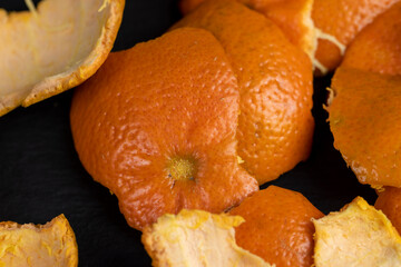 a large number of orange citrus fruits on a black slate surface