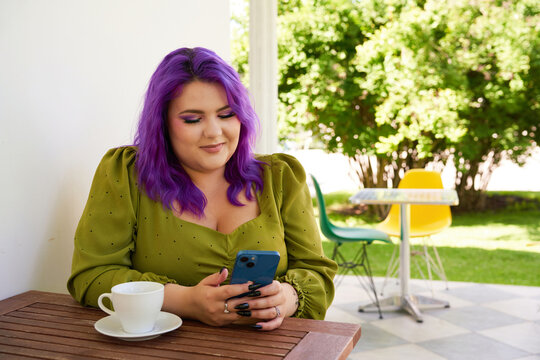 Girl with colored hair sitting with a smartphone in a caf&eacute;
