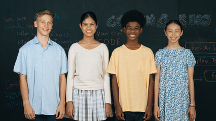 Group of smart multicultural teenager looking at camera at blackboard. Happy diverse children...