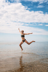 Happy sporty woman jumping in the water of sea - 753883961