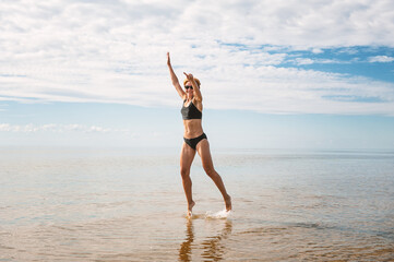 Happy sporty woman jumping in the water of sea - 753883970
