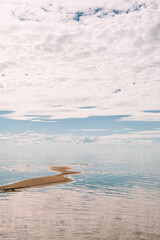 Beautiful seascape with sky reflected in the water and strip of land - 753883982