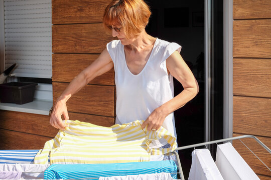 Female drying clothes on a clothesline at balcony