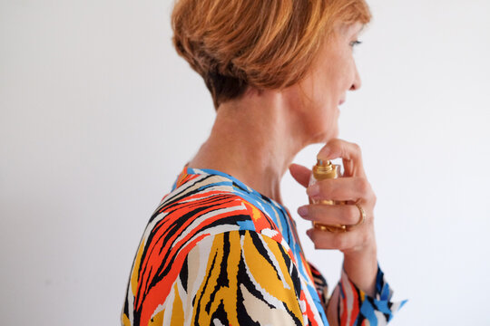 An adult woman putting on a perfume
