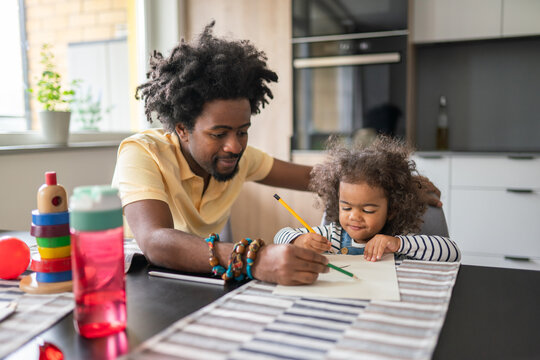 Father Helping His Daughter To Draw At Home