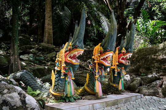 Naga statues covered in Buddhist prayer flowers at a park in Thailand