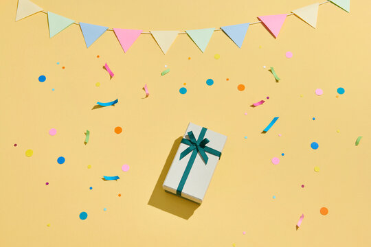Birthday party with gifts and confetti on yellow background