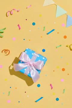 Birthday party with gifts and confetti on yellow background