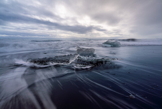Block of ice being hit by a wave at J&ouml;kuls&aacute;rl&oacute;n beach, Iceland.
