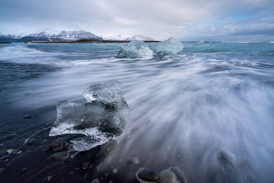 Block of ice being hit by a wave at J&ouml;kuls&aacute;rl&oacute;n beach, Iceland.