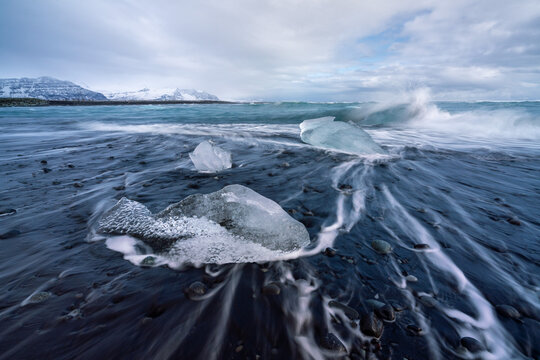 Block of ice being hit by a wave at J&ouml;kuls&aacute;rl&oacute;n beach, Iceland.