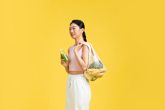 young woman carries fresh vegetables in string mesh bag