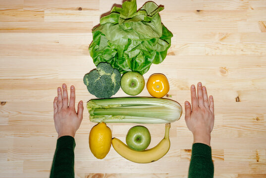 Set of fruits and vegetables with hands on table 
