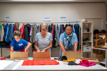 two smiled women and  granddaughter volunteering at donations center