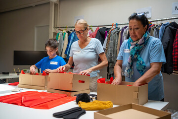 two smiled women and  granddaughter volunteering at donations center