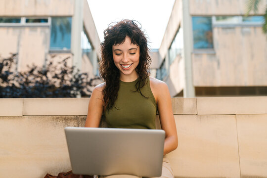 Happy, smiling young student with laptop computer in open air