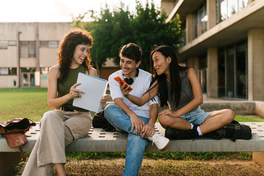 University classmates sharing notes together on a bench