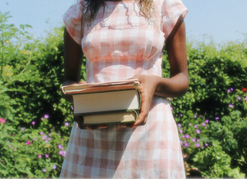 Girl in garden with pink plaid dress and books 3