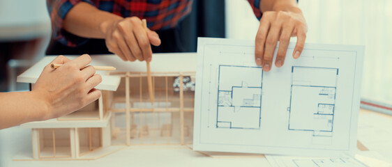 Cropped image professional architect hand compare construction between blueprint and house model...