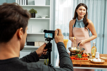 Cameraman recording to woman in chef influencer host cooking spaghetti with meat topped tomato...