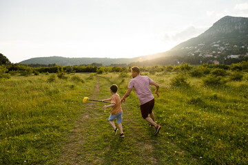 Man and little son play in mountain valley