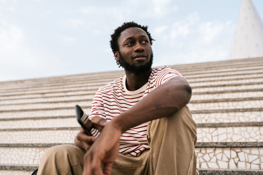 Positive African American guy sitting on stairs