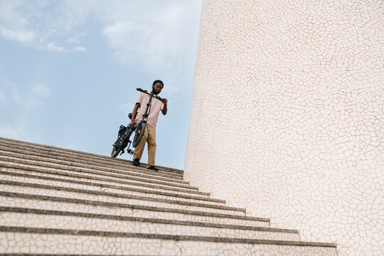 Black male carrying e bike down stairs