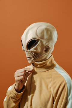 alien zipping up his beige jacket