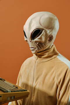 alien sitting in front of an old computer
