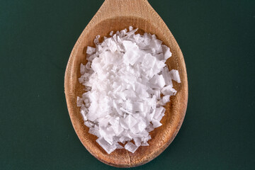 Natural Seasoning: 4K Ultra HD Image of White Salt in Wooden Spoon on Green Background