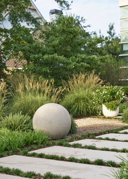 Modern farmhouse front yard with native landscaping a modern statue