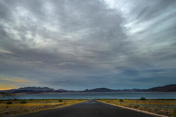 Desert Serenity: 4K Ultra HD Image of Desert Road Leading to Lakeshore with Clouds at Sunset