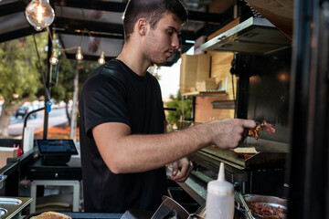 Chef Adding Bacon to Sandwiches on Food Truck