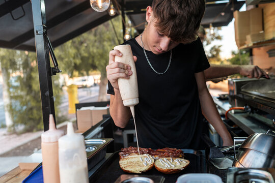 Chef Applying Sauce to Burger in Food Truck