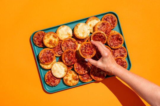 Woman holding mini pizza appetizers on colorful background