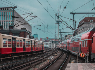 Obraz premium Trains arte leaving and approaching the station of Berlin Friedrichstrasse station on a cool spring day. Typical houses and TV tower visible in the background. Train transport in germany