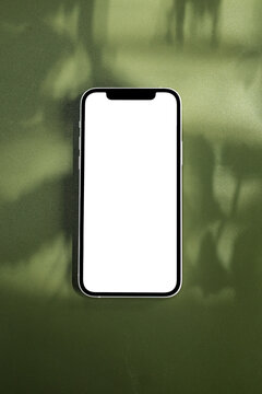 A mock-up of a mobile phone with a white screen on a green table
