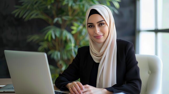 A Professional Middle Eastern Woman Executive. Wearing a Hijab. Working on a Laptop in a Corporate Office