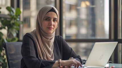 A Professional Middle Eastern Woman Executive. Wearing a Hijab. Working on a Laptop in a Corporate Office - obrazy, fototapety, plakaty