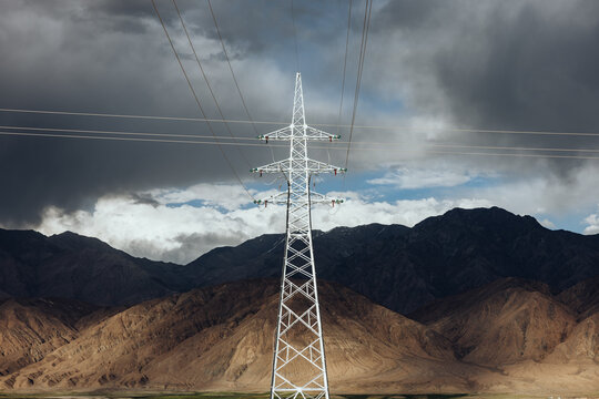 Electricity Pylons Against Stormy Mountain Backdrop