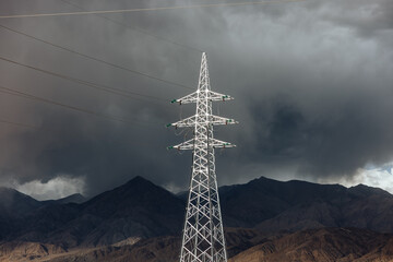 Electricity Pylons Against Stormy Mountain Backdrop