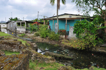 Fototapeta na wymiar Maisons avec rivière polluée et pont de fortune, Colon, Panama, horizontal