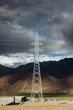Electricity Pylons Against Stormy Mountain Backdrop
